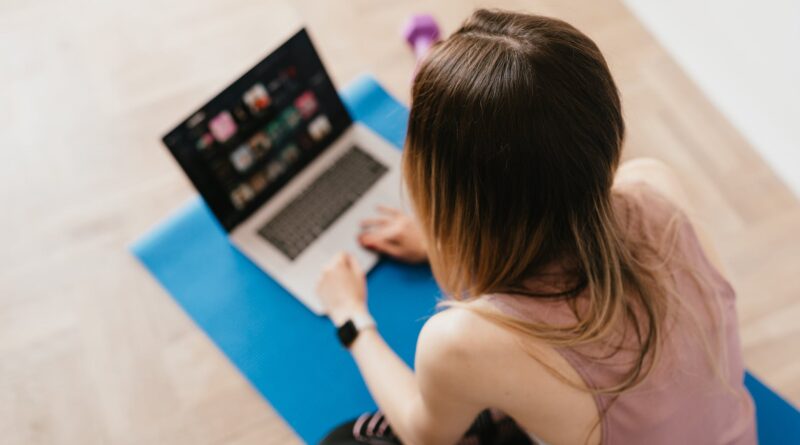 woman sitting on mat and surfing internet on laptop
